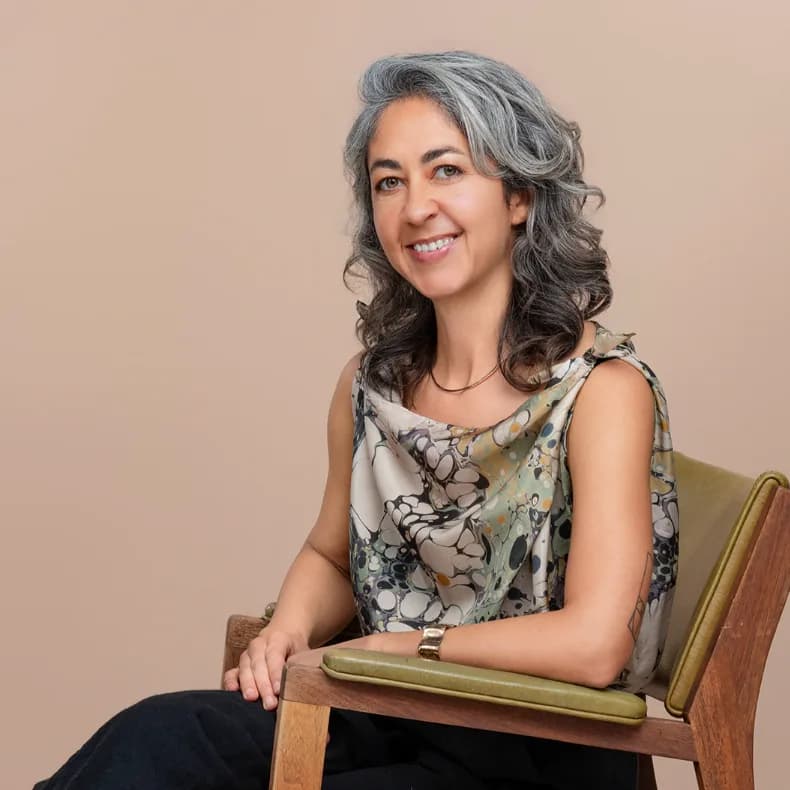 Seated corporate headshot on a warm neutral backdrop