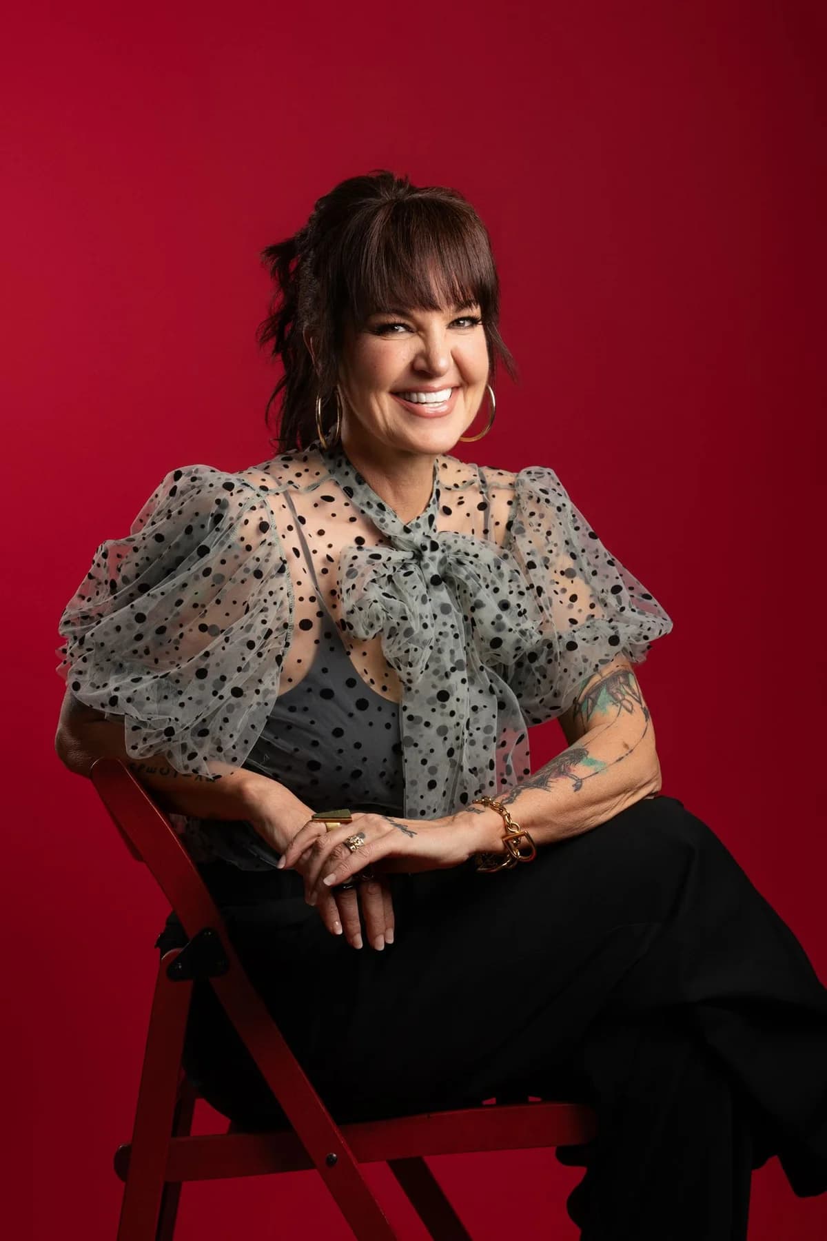 Woman seated on a stool against a rich red studio backdrop