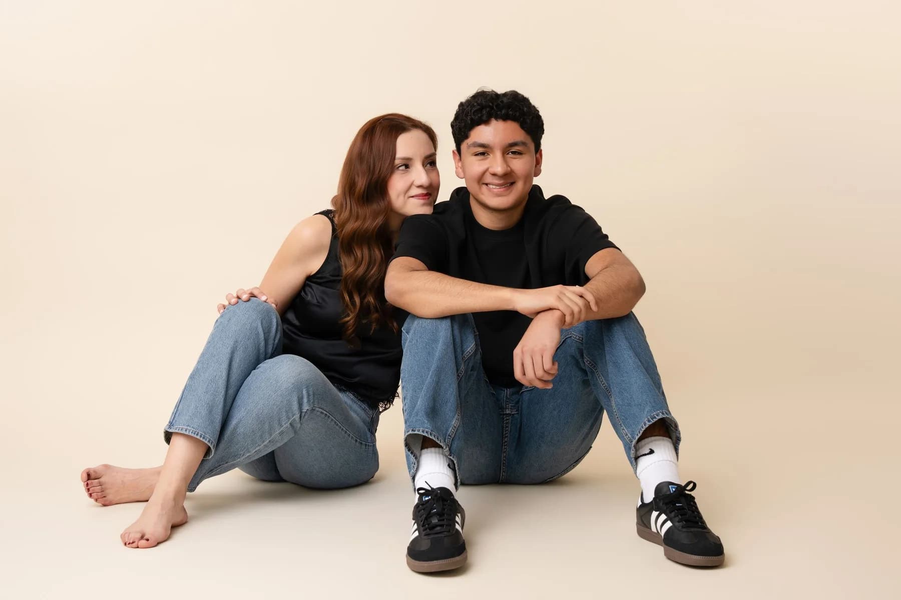 Family seated together on a studio floor against a neutral backdrop