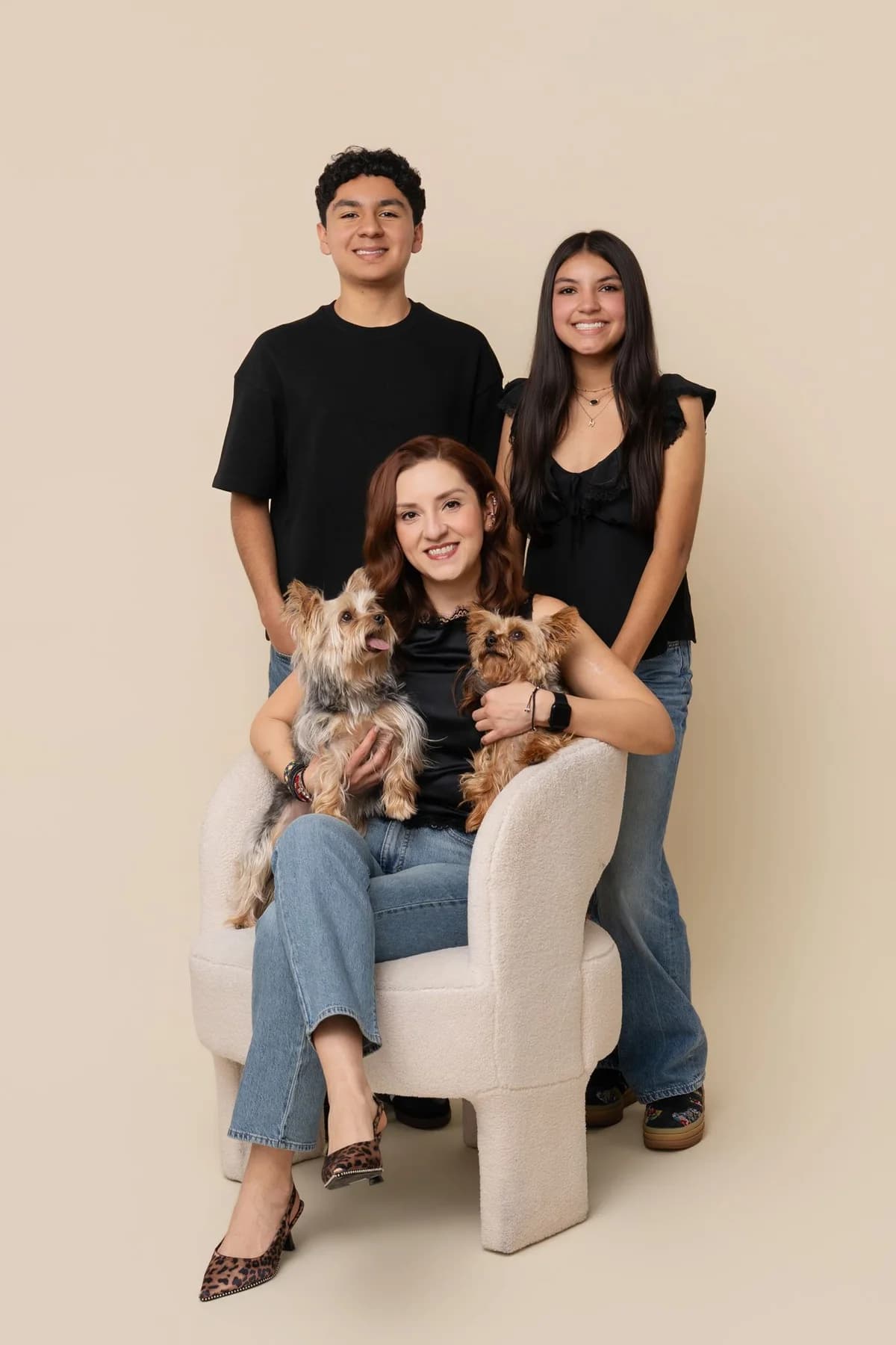 Family posed together with their dogs against a warm neutral studio backdrop