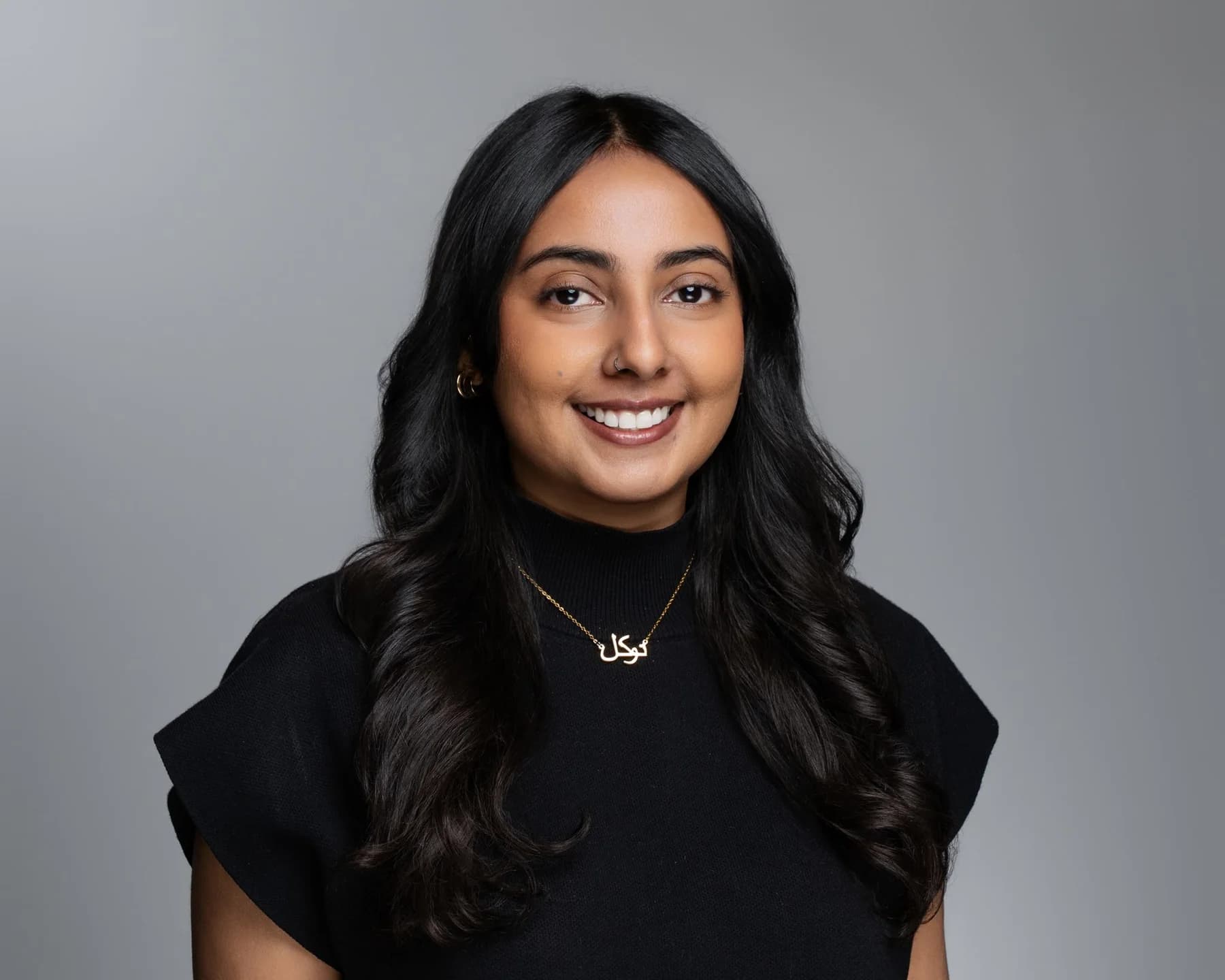Female team member with long dark hair against a gray studio backdrop
