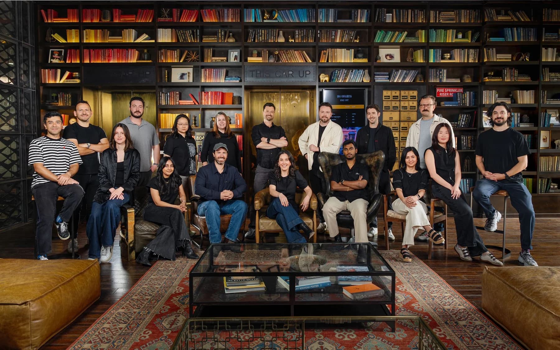 Company team standing and seated together in front of floor-to-ceiling library shelves