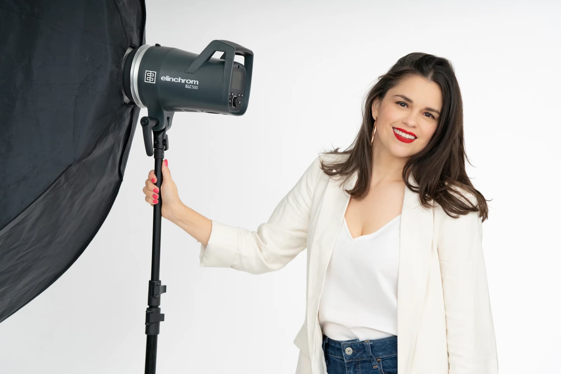 Lucero Valle beside a studio light and softbox, wearing a white blouse